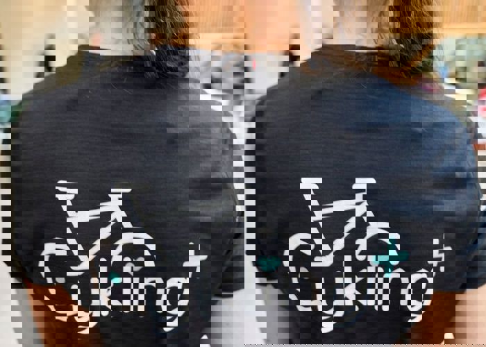 Ryggen på en sort T-shirt med logoet for Cykling+